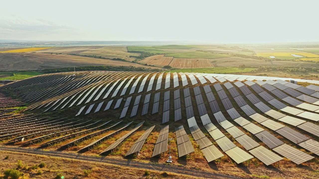Solpaneler dækker en bakke i et landområde under solnedgang, der opfanger sollys til energiproduktion og bidrager til vedvarende energikilder.