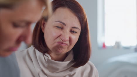 close up of woman making funny face during lively conversation with friend indoors, showing playful expression with raised eyebrows and smirk while maintaining cheerful communication