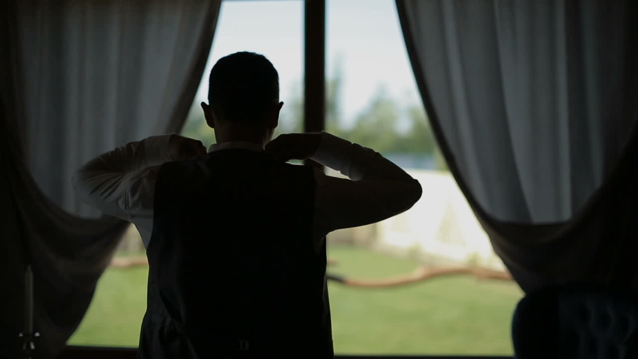 Man in a white shirt dresses trendy jacket. Window in the background.