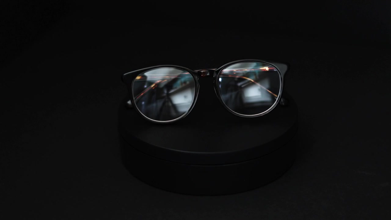 brown and green tortoiseshell round prescription glasses rotating 360 degrees against a black background