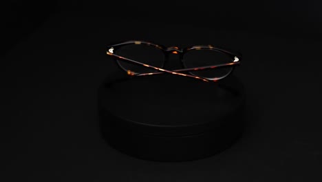 brown and green tortoiseshell round prescription glasses rotating 360 degrees against a black background