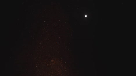flames of big campfire in front of large group of people at night, close up full moon tribal pagan gathering