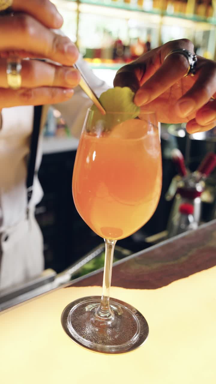 Barman che guarnisce un rinfrescante cocktail all'arancia con una foglia verde