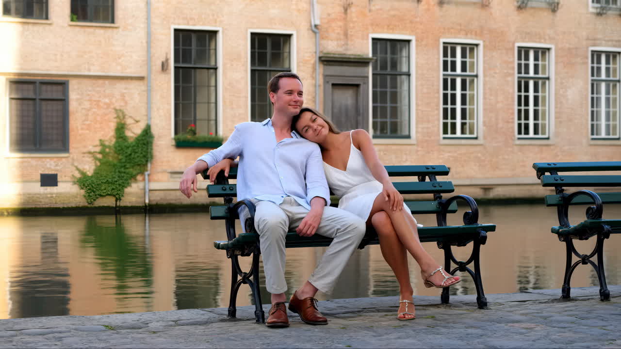 Coppia felice che si rilassa su una panchina lungo un canale in una città europea.