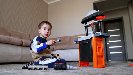 child plays with toy kitchen. a young child plays with a toy kitchen set, experimenting with tools and accessories in a cozy living room environment