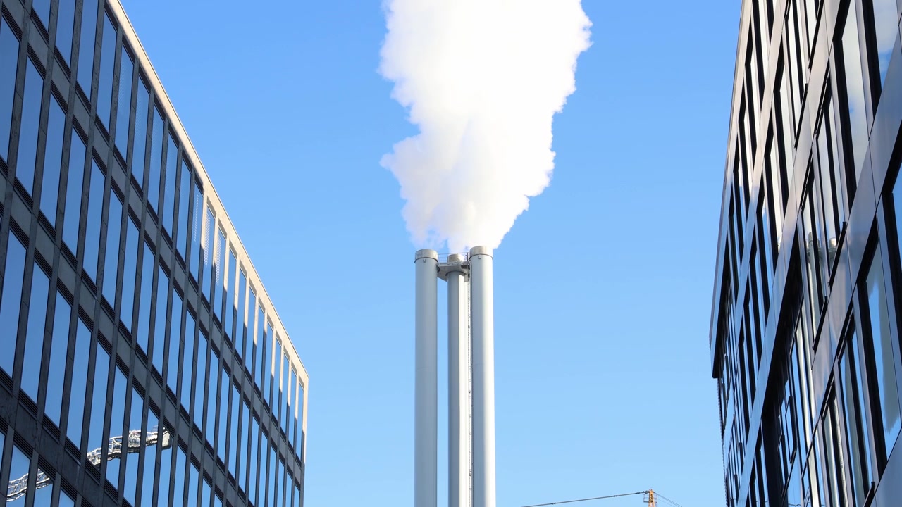 都市で大気を汚染する工場をクローズアップで捉えた情景。