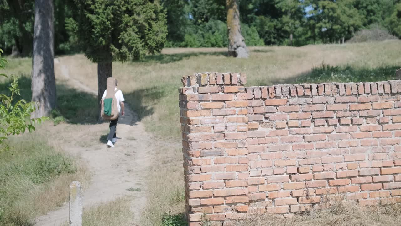 숲 근처의 거리에서 기타를 들고 는 젊은 남자
