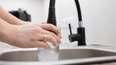 Gießendes-Glas-Wasser-Mit-Modernem-Küchenwassermischer,-Nahaufnahme