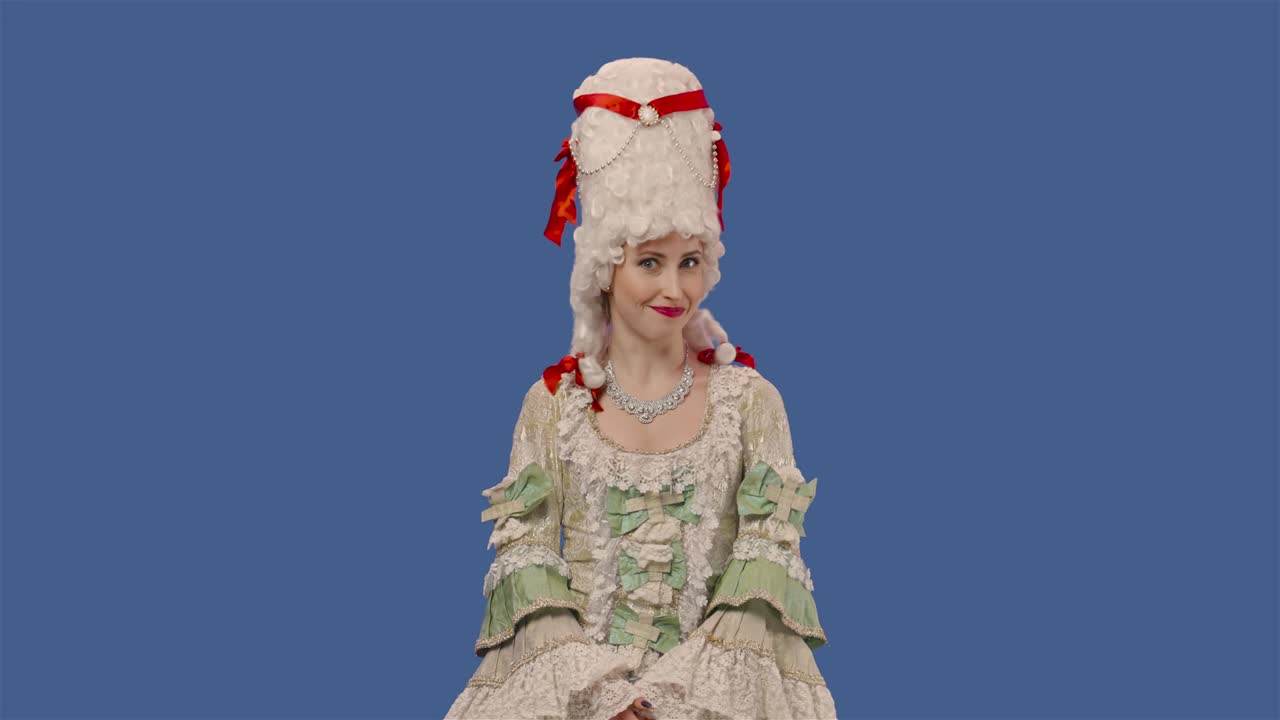 색 빈티지 렌즈 드레스와 위그를 입은 궁정 여인의 초상화: 을 고 거품을 불어넣는 젊은 여성이 블루 스크린 배경으로 스튜디오에서 포즈를 취하고 있습니다.