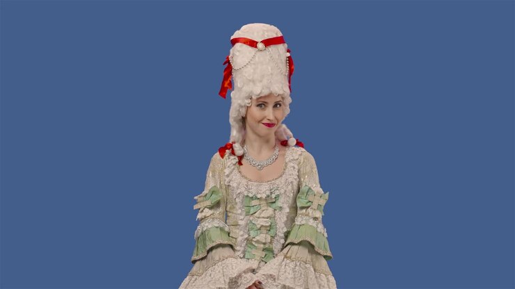 Portrait of courtier lady in white vintage lace dress and wig is chewing gum and blowing bubbles. Young woman posing in studio with blue screen background. Close up. Slow motion ready 59.94fps