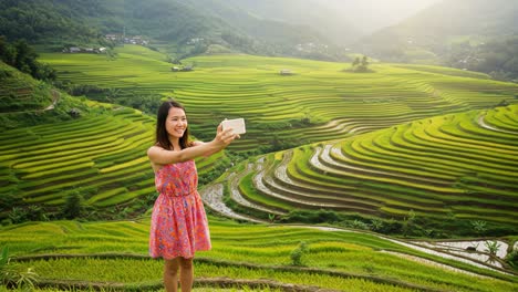 a young woman captures a vibrant selfie amidst breathtaking terraced rice fields, showcasing the stunning landscape and her joyful spirit in the golden hours of the day