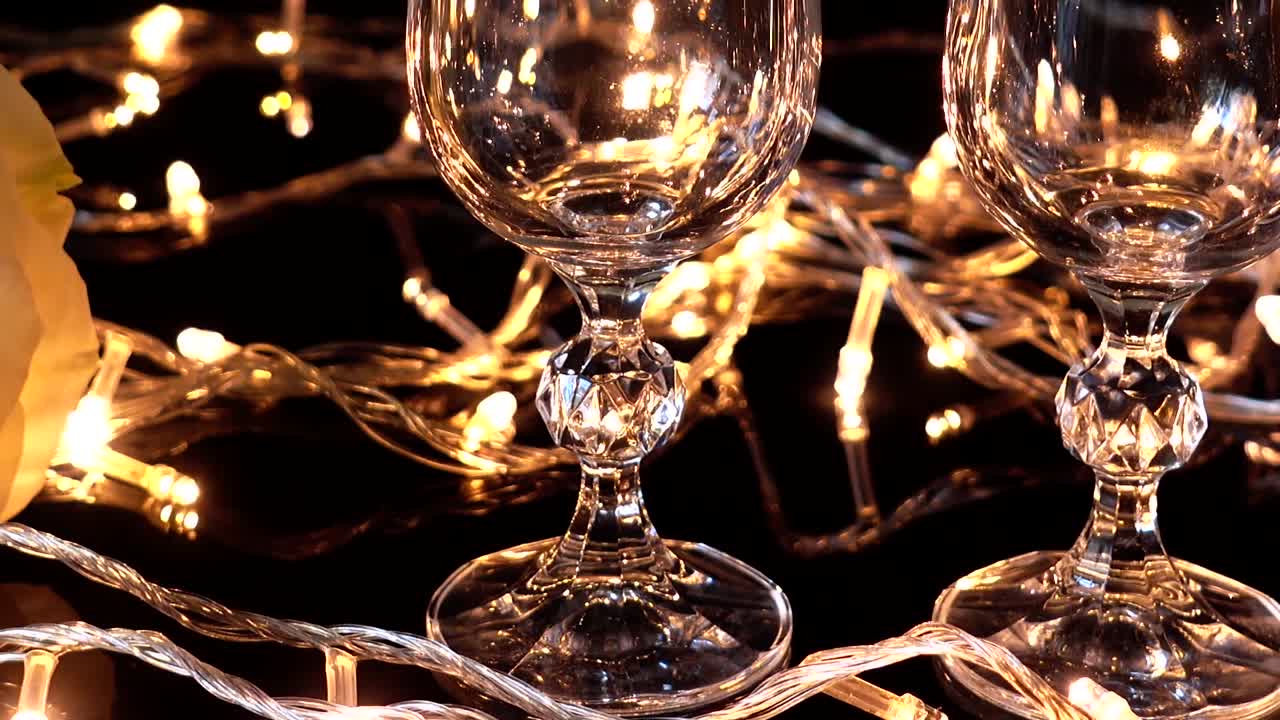 Des flûtes à champagne et une rose sur fond de guirlandes lumineuses
