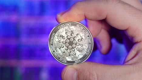 portrait of cardano ada silver coin being held between fingers