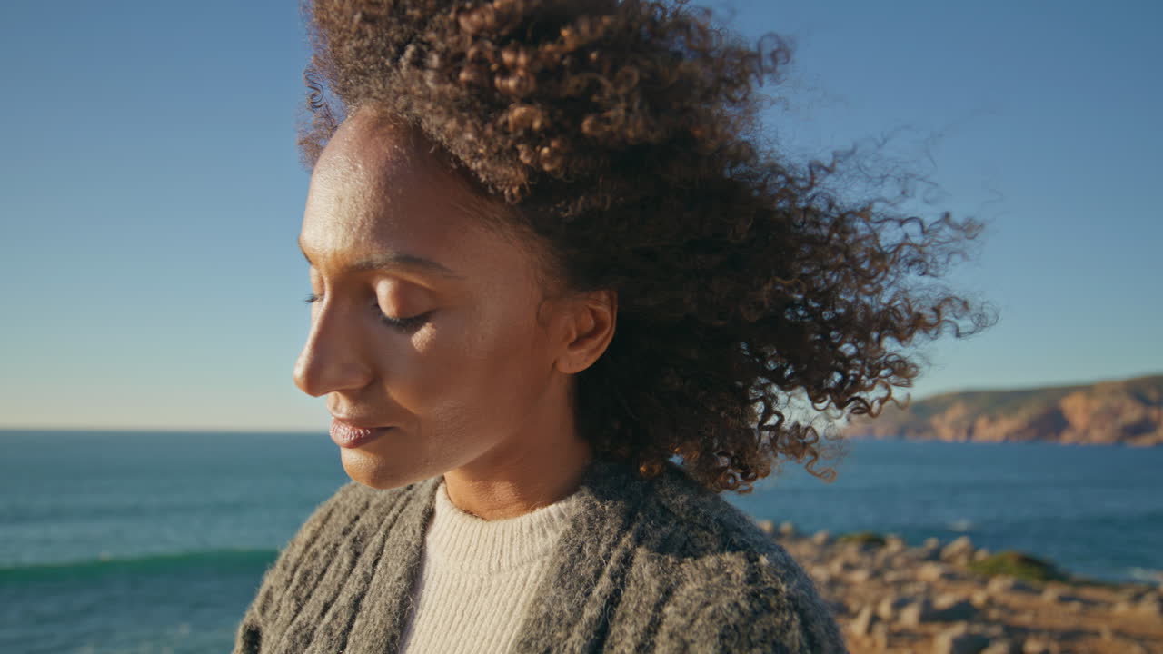 Gorgeous tourist contemplating sea at marine cliffs closeup. Curly hair model