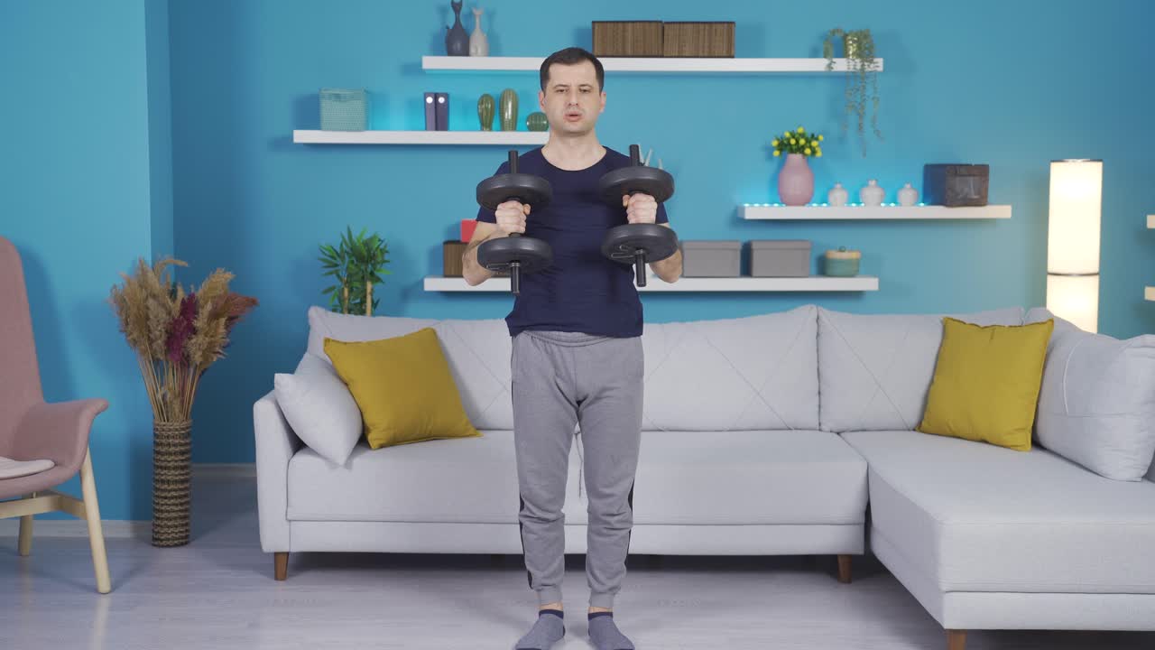성숙한 남자가 집에서 근력 훈련 운동을 하고 있습니다.