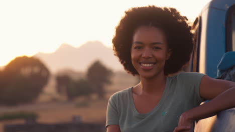 Portrait-Of-Woman-Standing-Next-To-Pick-Up-Truck-On-Road-Trip-To-Cabin-In-Countryside