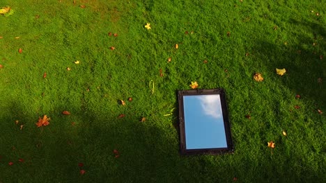 Drone-aerial-ascending-view-of-mirror-on-the-grass-with-reflection-of-the-cloudy-sky-on-a-autumn-afternoon