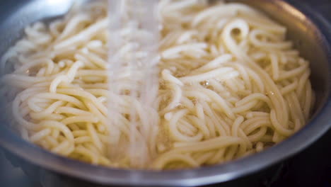 Rinsing-a-pot-of-spaghetti-in-the-kitchen-sink