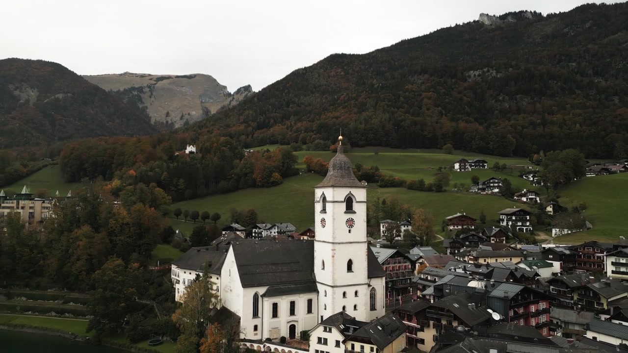 Drohnenaufnahme von Sankt Wolfgang im Salzkammergut an einem bewölkten und nebligen Tag bei dunkelgrünen Bergen.