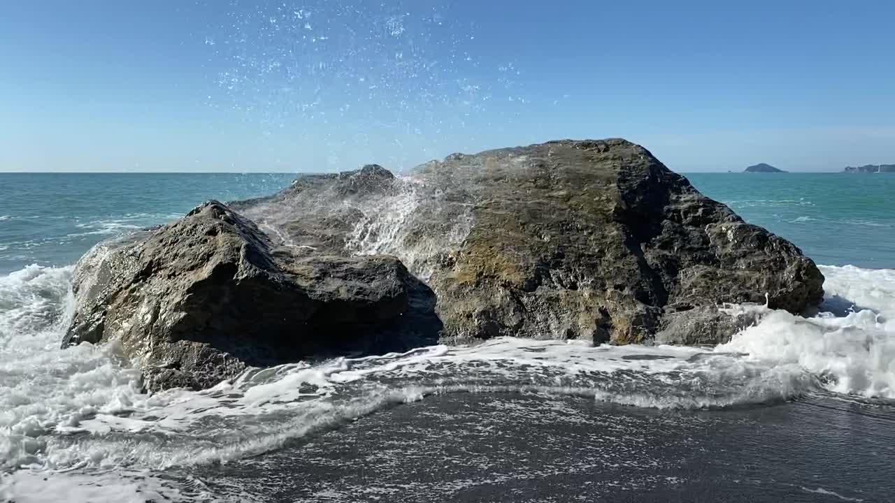 Waves crashing on a big rock on the beach in Liguria, Italy. Slow Motion
