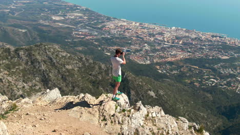 Tall,-blonde-man-taking-professional-photos-of-Marbella-from-the-top-of-La-Concha-in-Spain