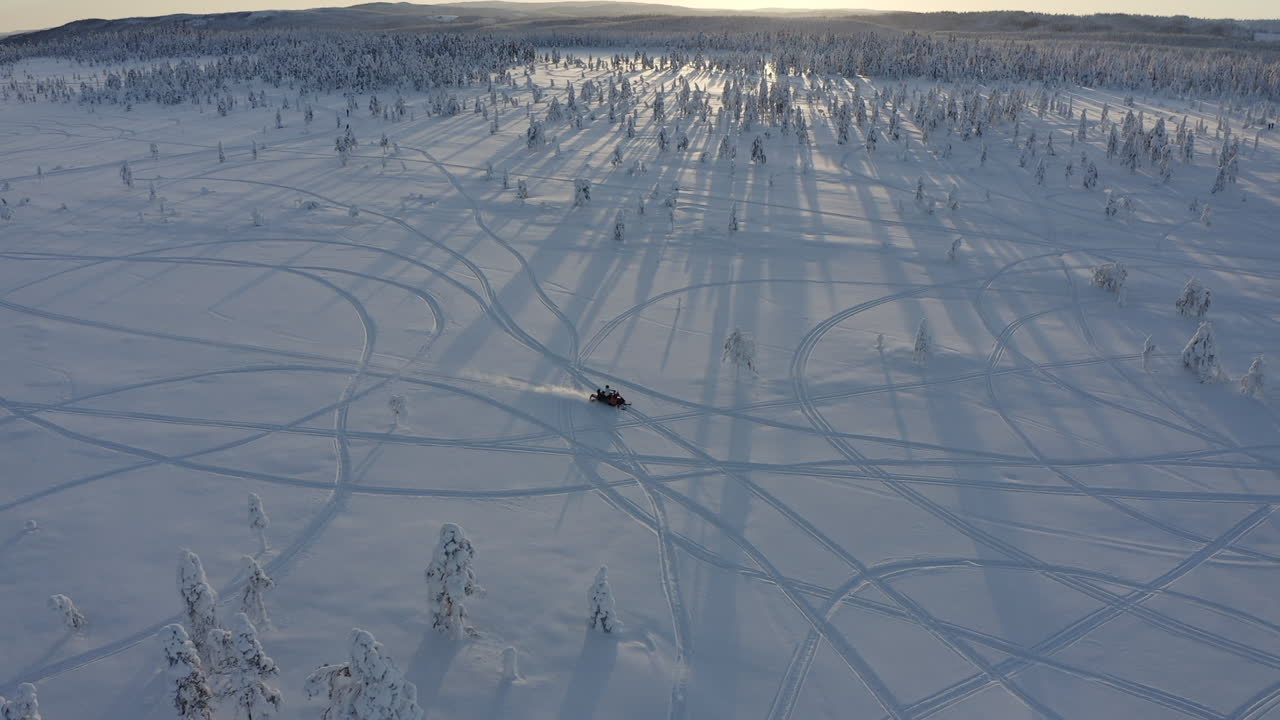 vista superior de la toma aérea de un dron de un paseo en moto de nieve en una pista nevada a través del frío bosque invernal en suecia