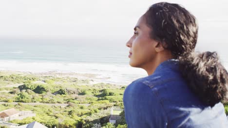 video de una mujer biracial pensativa por el mar mirando a la distancia