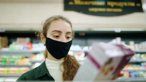 mujer compradora con máscara protectora eligiendo alimentos en la tienda de comestibles