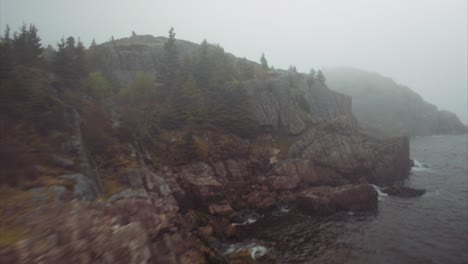 rocky cliffs line a narrow entry to protected port hidden by morning fog