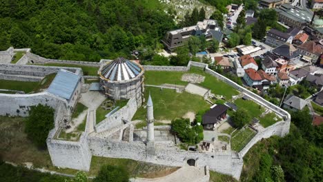 sweeping aerial shot over travnik’s medieval stari grad old town fortress perched above the city, top down view