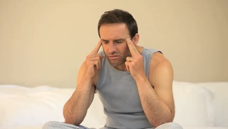 Man-having-a-headache-sitting-on-the-bed