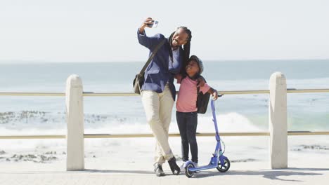 Video-Eines-Glücklichen-Afroamerikanischen-Vaters-Und-Sohnes-Mit-Roller,-Die-Ein-Selfie-Auf-Der-Promenade-Machen