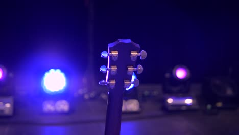 close-up of a guitar headstock on a concert stage