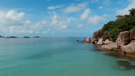 fly forward slowly above water rocks on side blue sky background thailand