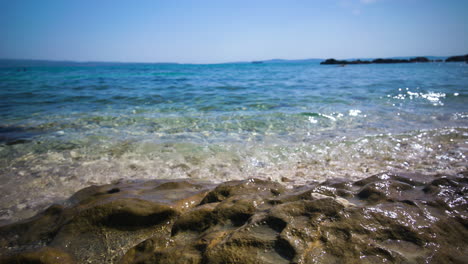 crystal clear calm water of the mediterranean breaks softly on a rocky beach