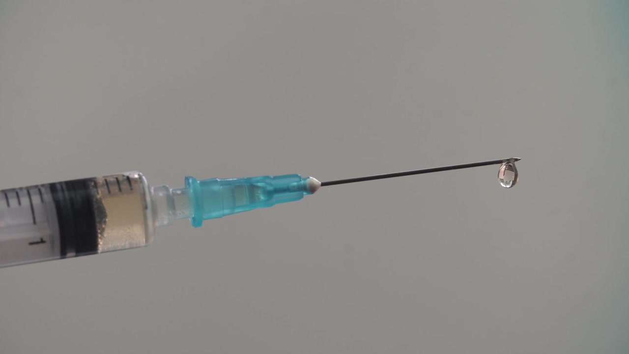 Close-up de agulha de seringa com uma gota de medicamento líquido