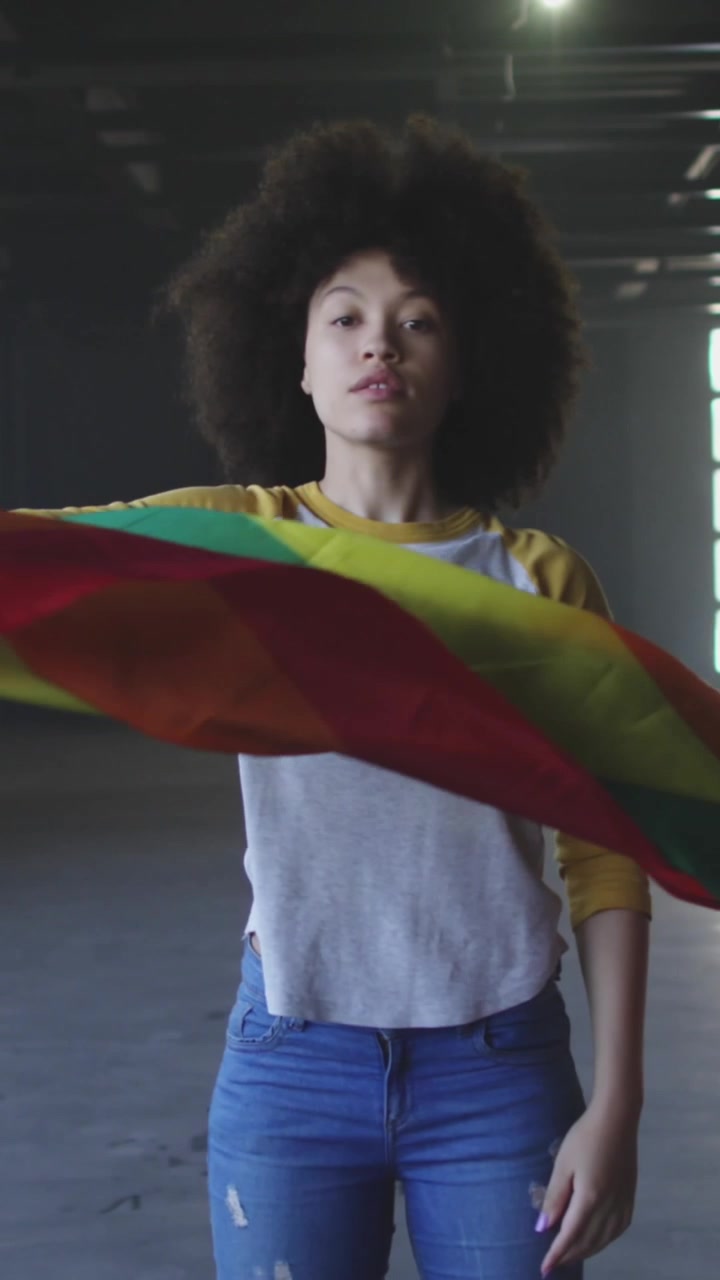 Animazione di orgoglio arcobaleno e unicorno su donna afroamericana con bandiera arcobaleno