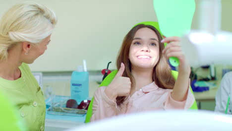 mujer comprobando sus dientes en el espejo después de un tratamiento dental en el consultorio del dentista