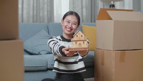 행복 한 여자 는 이동 중 에 모형 집 을 들고 있다