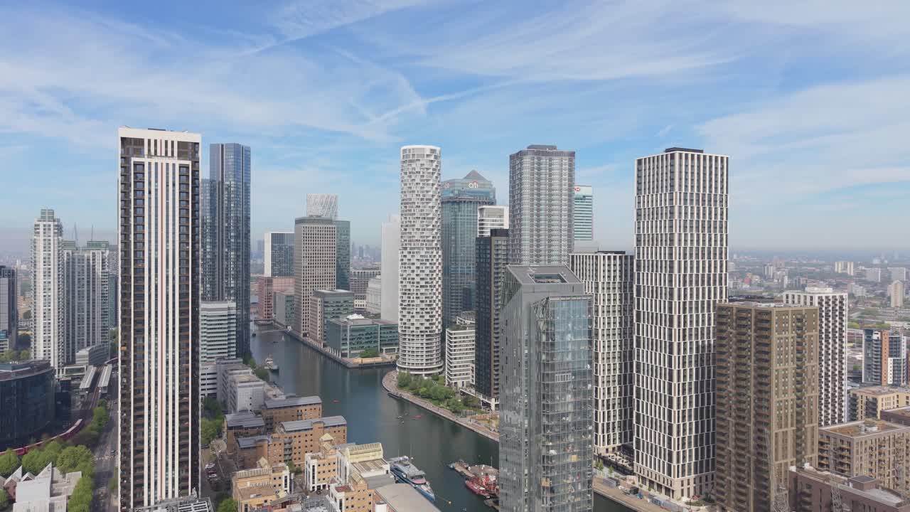 Una veduta panoramica aerea del quartiere finanziario di Canary Wharf a Londra. Alti e moderni grattacieli si ergono lungo un fiume sinuoso, dove attraccano le barche.