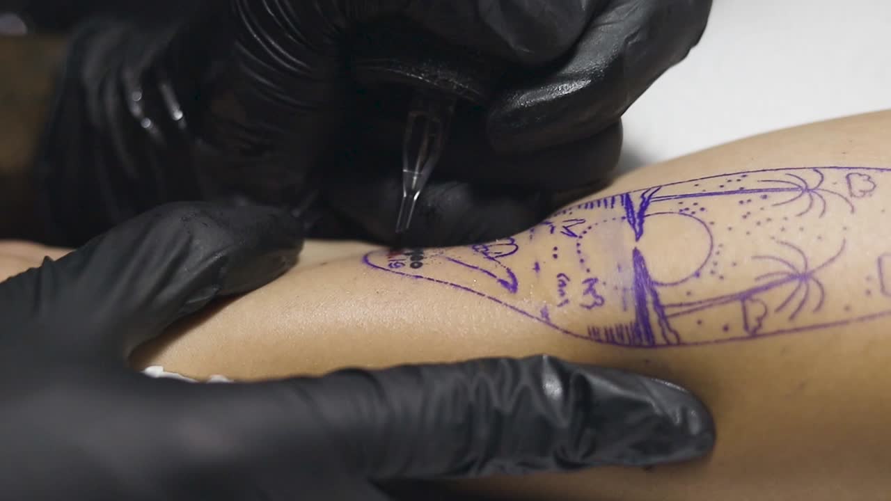 close up angle view of an unrecognisable man having a tattoo drawn and inked onto his arm, artist using a tattoo gun to tattoo the black ink into his skin.
