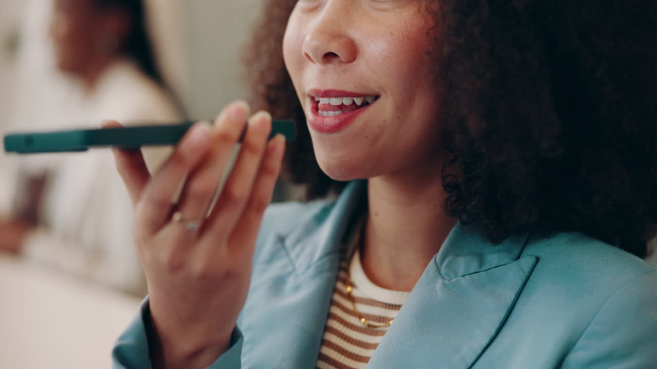 A smiling businesswoman uses her phone to record a voice message in a meeting