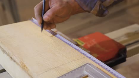 close-up of crumpled carpenter hands measuring wood with meter.