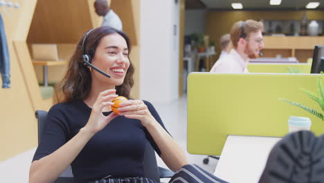 businesswoman wearing headset playing with stress ball talking to caller in customer services centre