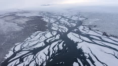 slow aerial flight over glacial river delta in iceland during foggy and cloudy day in winter - snowy landscape with eldvatn river