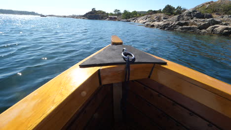 Tip-Of-A-Sjekte-Wooden-Boat-And-The-Blue-Sea-With-The-Rocky-Coastline-On-A-Sunny-Day-In-Arendal,-Norway