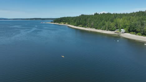 Vista-Aérea-De-Un-Pequeño-Kayak-Amarillo-Remando-En-Lakebay,-Washington