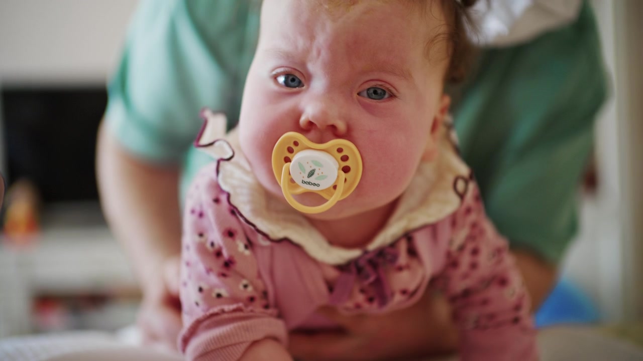 Bebê deitado relaxado em uma superfície macia enquanto é tocado suavemente por um cuidador