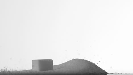 sugar cube falling into pile of sugar on white background