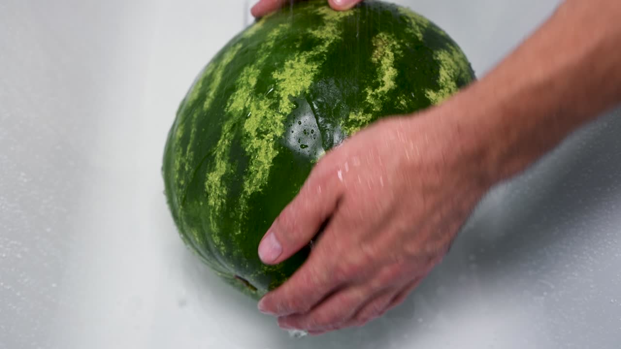 한 남자가 은 수박을 손으로 고 있습니다.